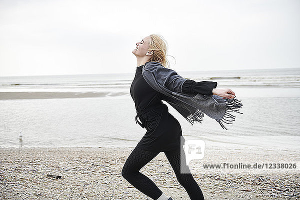 Netherlands  happy blond young woman running on the beach