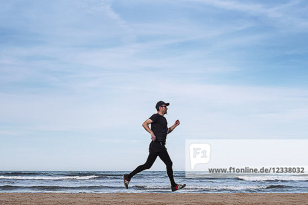 Spain  man dressed in black jogging on the beach