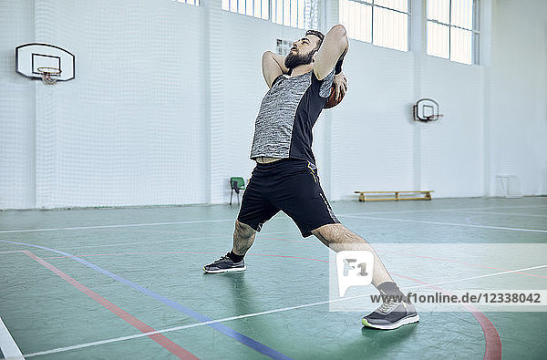 Man with basketball  stretching  indoor