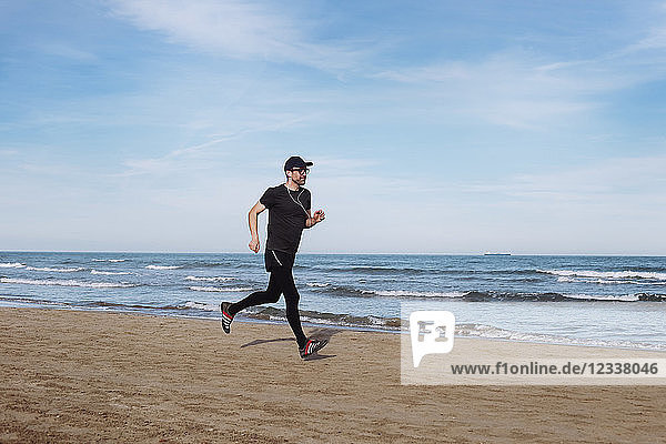 Spain  man dressed in black jogging on the beach