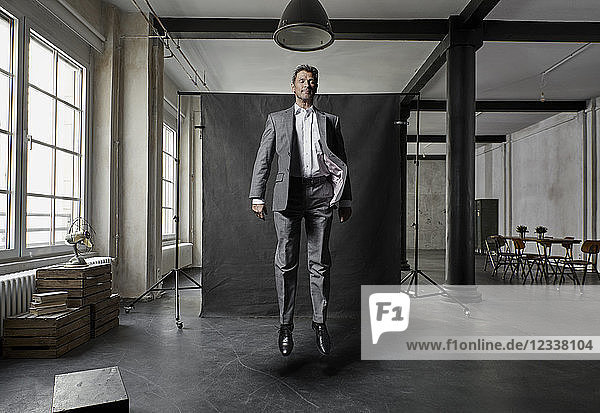 Mature businessman floating in front of black backdrop in loft