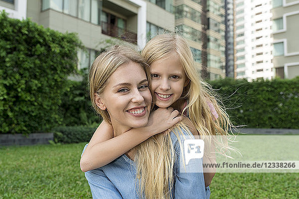 Happy mother and daughter hugging and smiling in urban city garden