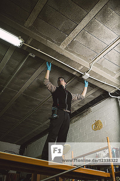Man working on conduit at the ceiling
