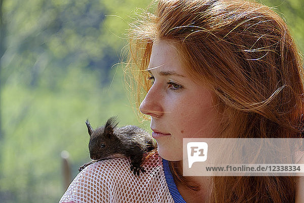 Portrait of redheaded teenage girl with squirrel on her shoulder