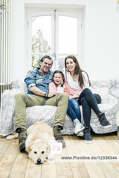 Portrait of happy family with dog in living room