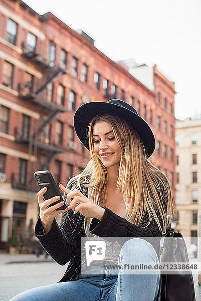 Frau schaut lächelnd auf Handy  schreibt SMS  New York  USA