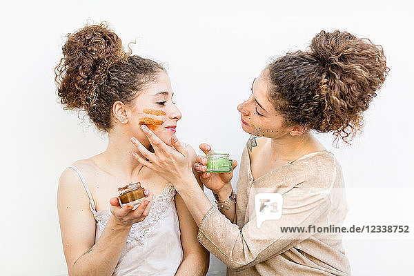 Fashion blogger twins applying face masks  white background