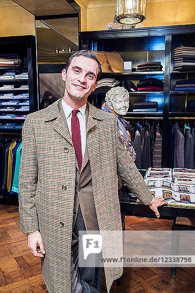 Male customer wearing traditional raincoat in tailors shop  portrait