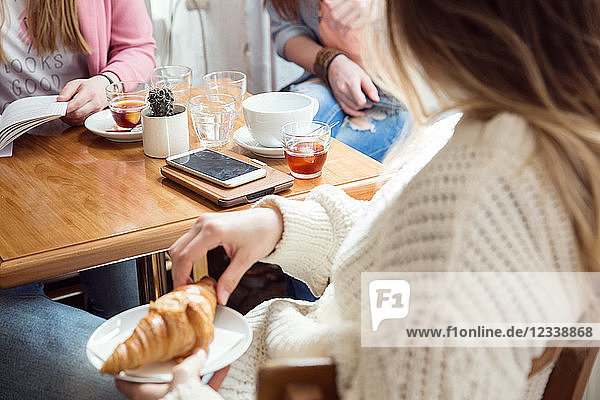 Frauen unterhalten sich bei Kaffee und Croissant im Café