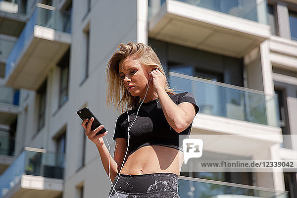 Junge Frau hört Musik auf dem Handy  Gebäude im Hintergrund