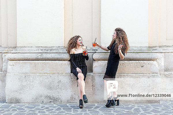 Mode-Blogger-Zwillinge stoßen mit Cocktail auf das Gebäude an
