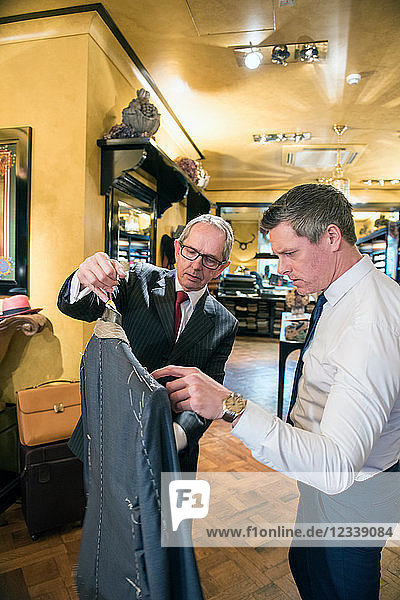 Tailor showing customer bespoke jacket in tailors shop