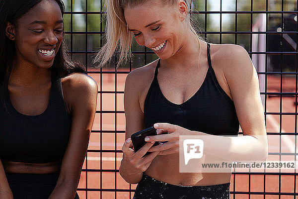 Junge Frauen lächeln  lesen Texte auf dem Handy