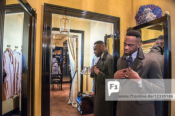 Junge männliche Kundin schaut im Spiegel in traditionelle Schneiderei
