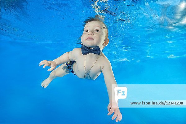 Litle boy swim underwater in the pool.