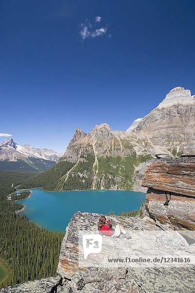 Female hiker enjoying view from high lookout on lake ohara. Lake O`Hara area Yoho National Park British Columbia Canada.