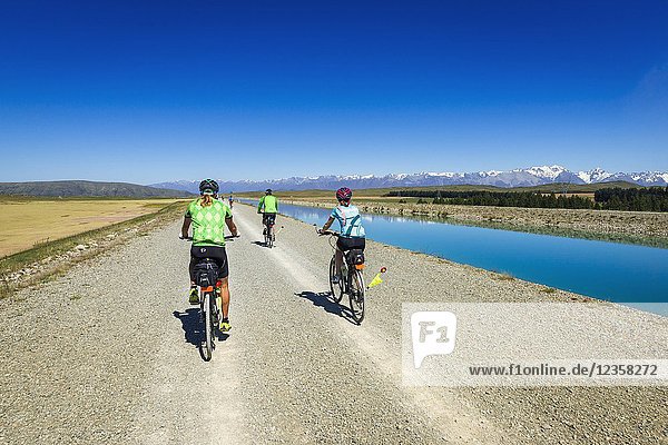 Cycling under the Southern Alps along the Tekapo Canal  Lake Tekapo  Canterbury  South Island  New Zealand.