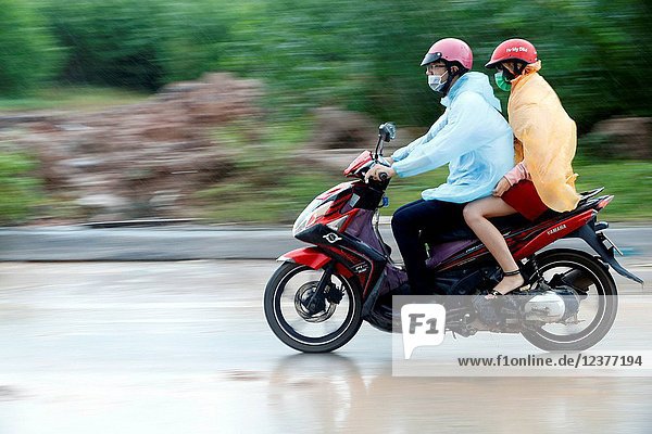 Heavy monsoon rain. Man and woman driving a motorbike.