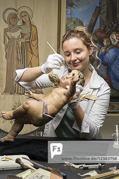 Restaurierungsatelier  Restauratorin  Frau reinigt einen Engel mit einem Pinsel  restaurierte Fastenschals im Rücken  München  Bayern  Deutschland  Europa