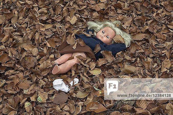 Symbolfoto des sexuellen Missbrauchs  Puppe mit hochgezogenem Rock und nacktem Unterleib im Laub liegend