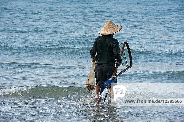 Fisherman wearing a straw hat  Cua Dai beach in Hoi An  Vietnam  Asia