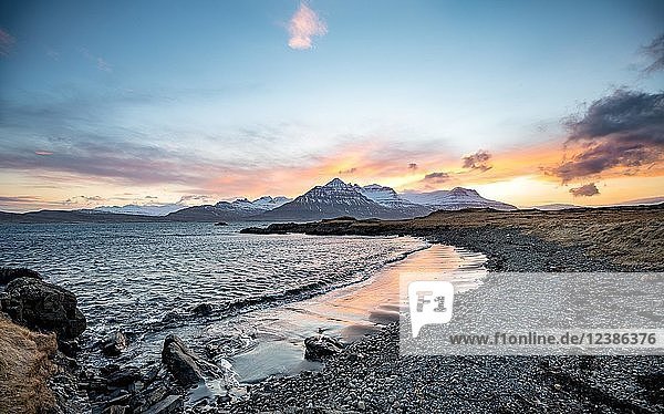 Sunset over snow covered mountains  small bay with black beach at the fjord Berufjörður  Austurland  East Iceland  Iceland  Europe
