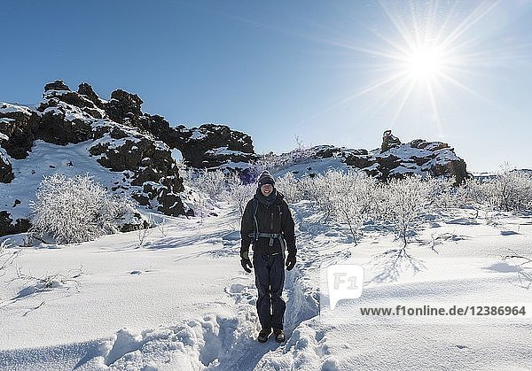Mann auf Wanderweg im Schnee bei Sonnenschein  verschneite Landschaft  verschneites Lavafeld  Vulkanlandschaft Krafla  Dimmuborgir Nationalpark  Mývatn  Island  Europa