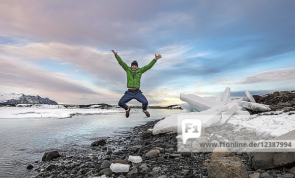 Wanderer springt  Eisschollen am Rande der Gletscherlagune Jökulsárlón  Gletschersee  Sonnenuntergang  Südrand des Vatnajökull  Südostisland  Island  Europa