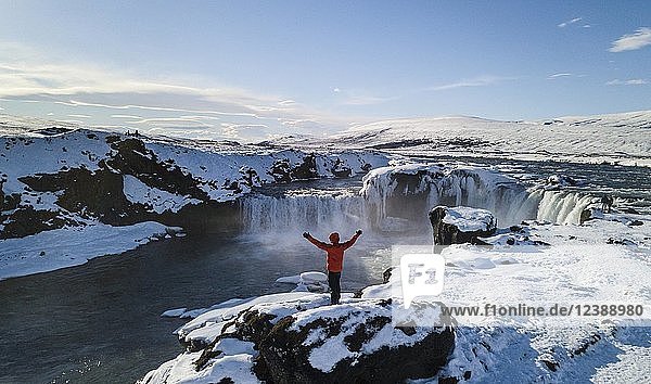 Luftaufnahme  Mann steht vor dem Wasserfall Góðafoss  Godafoss im Winter mit Schnee und Eis  Norðurland vestra  Nordisland  Island  Europa
