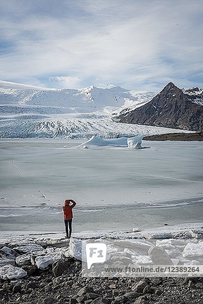 Man stands at frozen lagoon with ice floe  mountains  Fjallsárlón Glacier Lagoon  South Iceland  Iceland  Europe