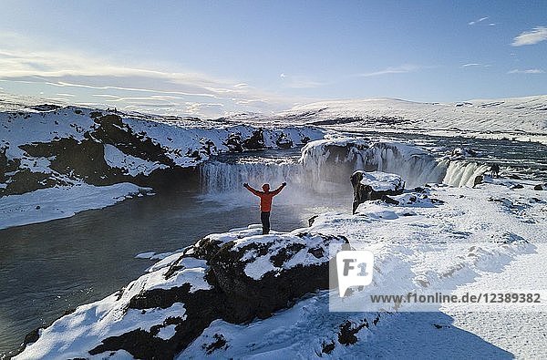Luftaufnahme  Mann steht vor dem Wasserfall Góðafoss  Godafoss im Winter mit Schnee und Eis  Norðurland vestra  Nordisland  Island  Europa