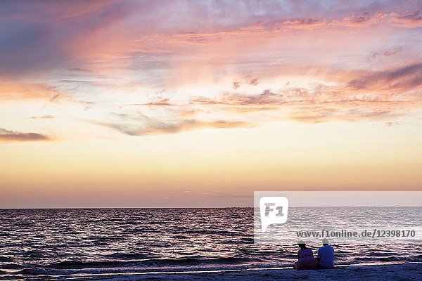 Florida  Fort Ft. Myers Beach  Gulf of Mexico  water  sunset  dusk  cloouds  dramatic lighting  pink  blue  man  woman  couple  watching  public