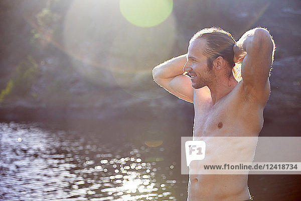Carefree bare chested man at sunny summer lake