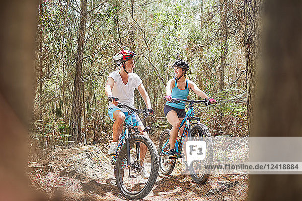 Father and daughter mountain biking on trail in woods
