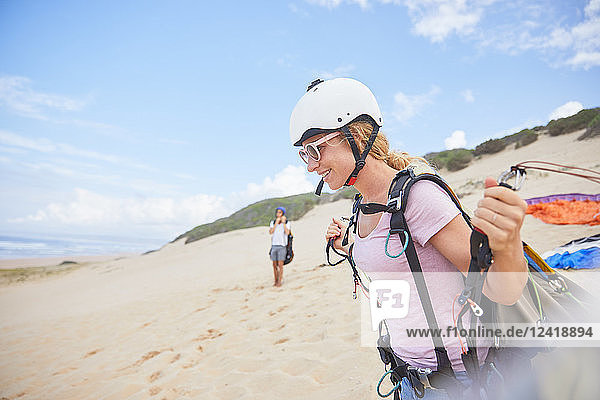 Smiling female paraglider with equipment on beach