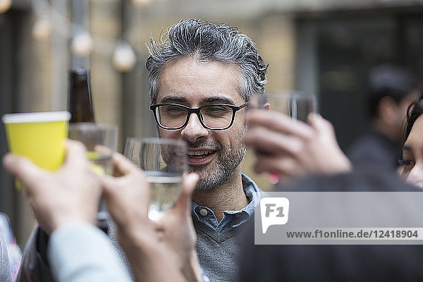 Happy man toasting drinks with friends at party