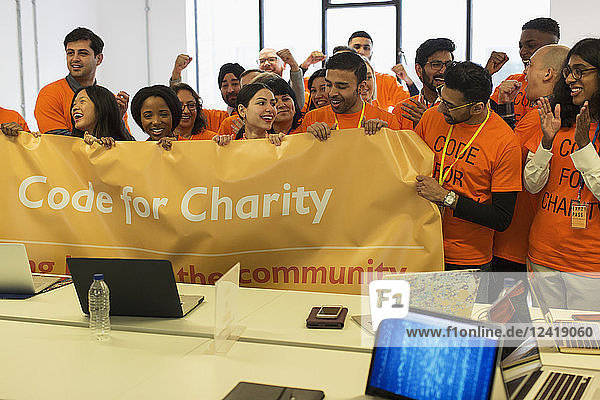 Hackers with banner cheering  coding for charity at hackathon