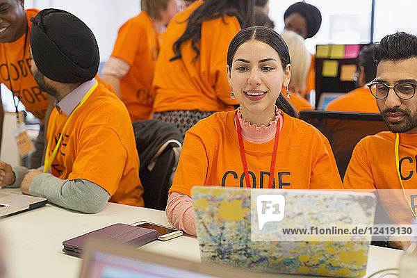 Hackers at laptop coding for charity at hackathon