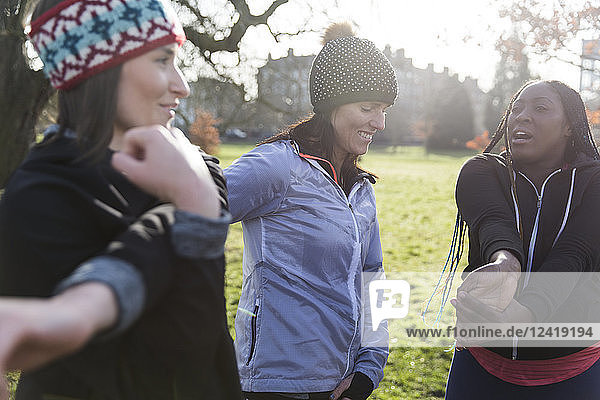 Female runners stretching in sunny park