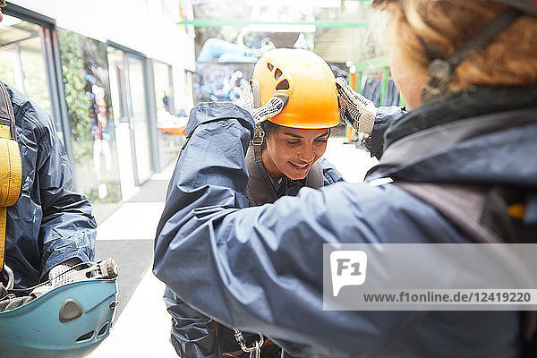 Woman helping friend with zip line helmet