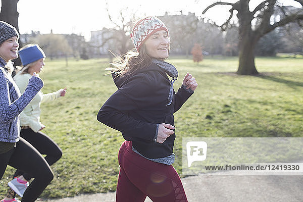 Confident female runner running in sunny park