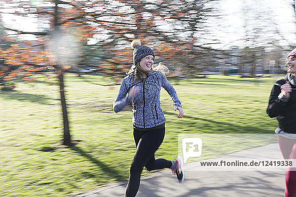 Smiling  confident female runner running in sunny park