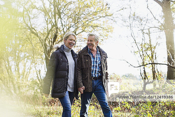 Happy mature couple holding hands  walking in sunny autumn park