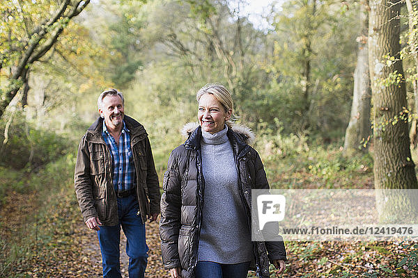 Lächelndes reifes Paar beim Spaziergang im sonnigen Herbstwald