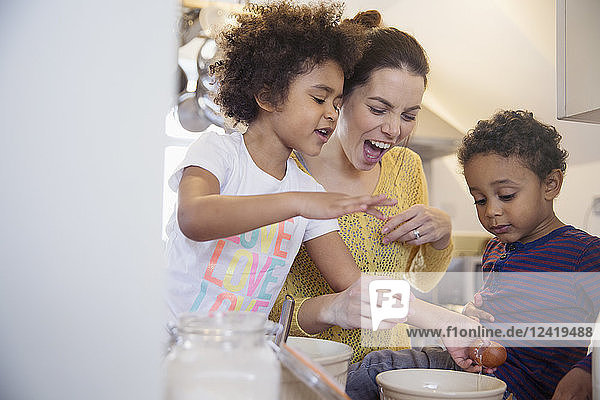 Playful mother and children baking in kitchen