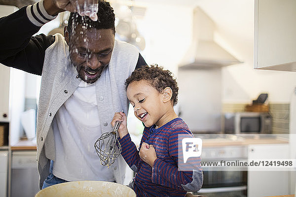 Playful father and son baking in kitchen