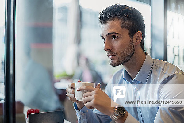 Young businessman drinking coffee in a cafe