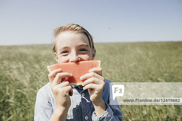 Happy boy on a field holding a watermelon