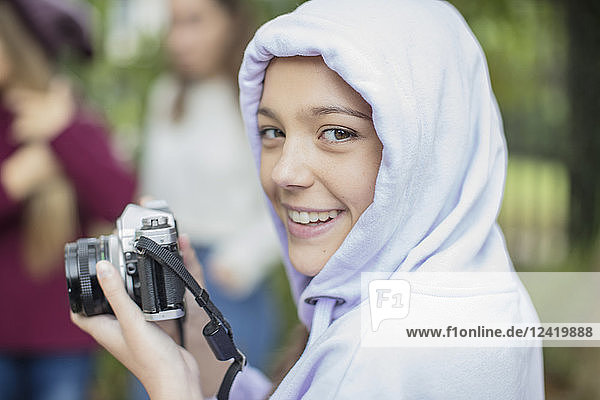 Portrait of smiling teenage girl with camera outdoors