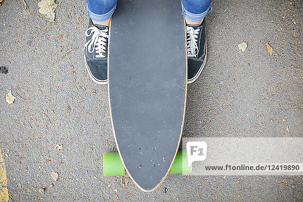 Close-up of feet next to skateboard